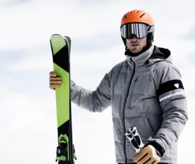 Man wearing helmet and ski goggles holding skis, portrait